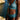 A woman wearing a teal lace bikini stands outdoors near rocky coastline and blue water, cropped from neck to upper thighs.